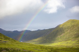 Grüne Berglandschaft mit Regenbogen